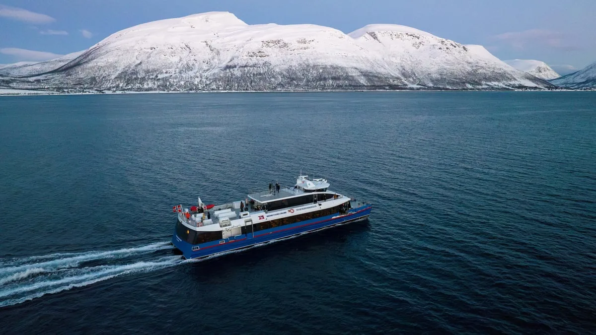 Catamaran sailing beside a snowy coastline