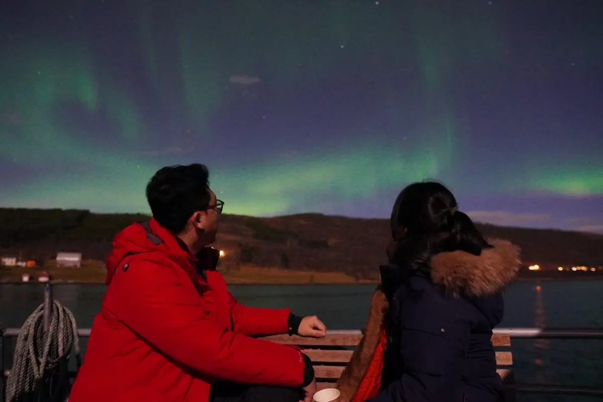Guest in a red jacket beneath the aurora