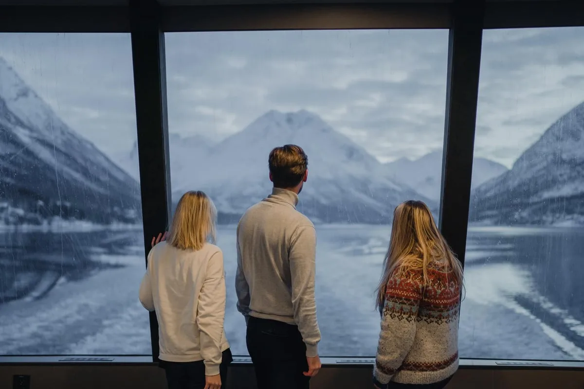 Guests watching the fjord through panoramic cabin windows
